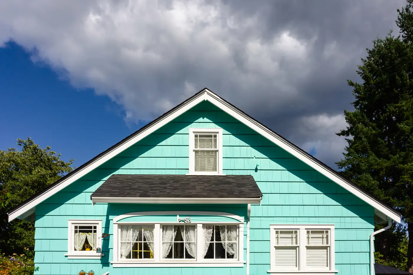 A brightly painted gabled home under a dramatic sky